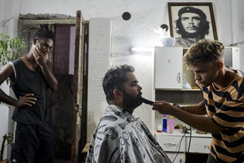 Um profissional apara a barba de um cliente numa barbearia de La Havana,...